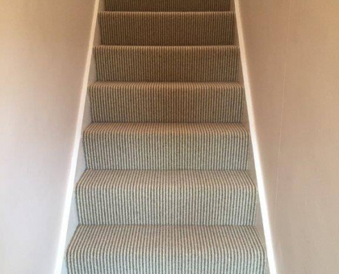 Winder staircase with wool mix loop stripe carpet viewed from bottom looking up staircase with curved winder steps