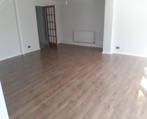 Oak effect laminate flooring in Redhill living room viewed from French doors looking into white walled interior space