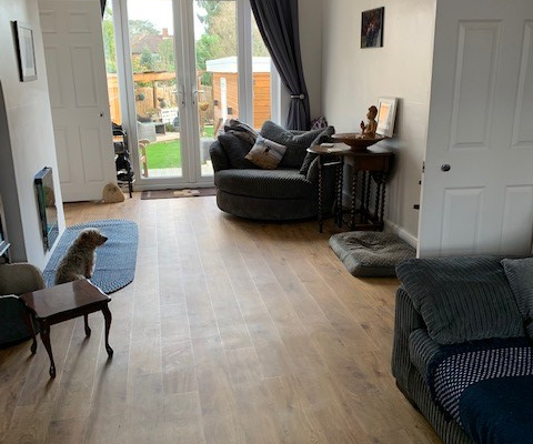 Reigate living room with golden oak LVT flooring leading to French doors and garden with large armchair seating area