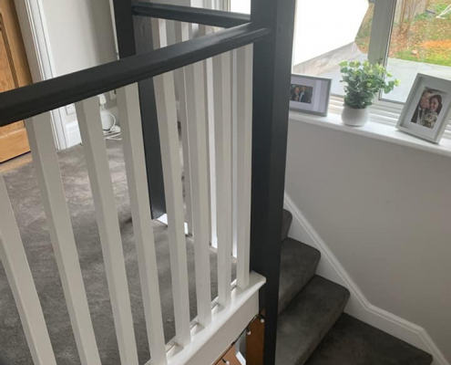Side view of Surrey landing with charcoal velvet carpet and staircase leading down with black and white handrail detail