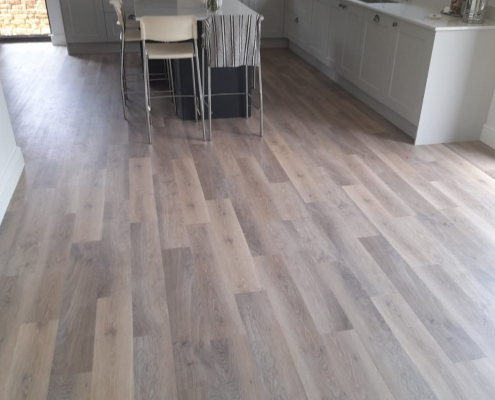 Close view of limed washed oak LVT flooring in front of kitchen units in Surrey showing light grey cabinetry