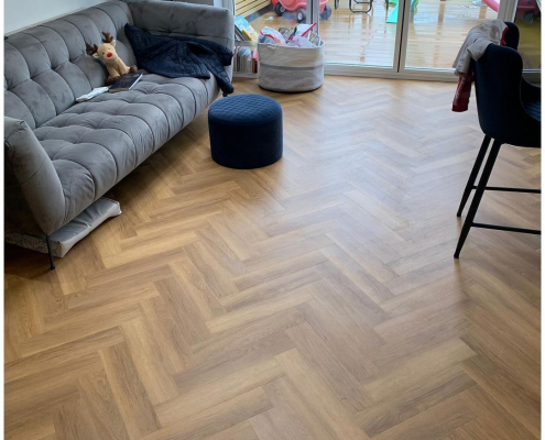 Honey oak herringbone LVT flooring in kitchen seating area with patio doors to garden in Surrey home