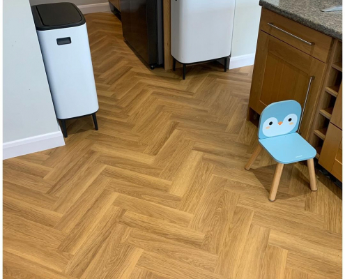 Herringbone LVT flooring in honey oak finish around kitchen island in Surrey home