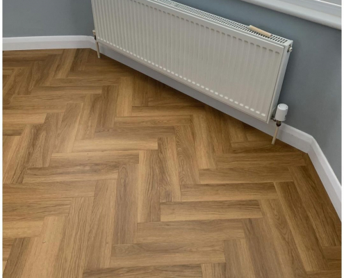 Close-up of honey oak herringbone LVT flooring near bay window in Surrey living room