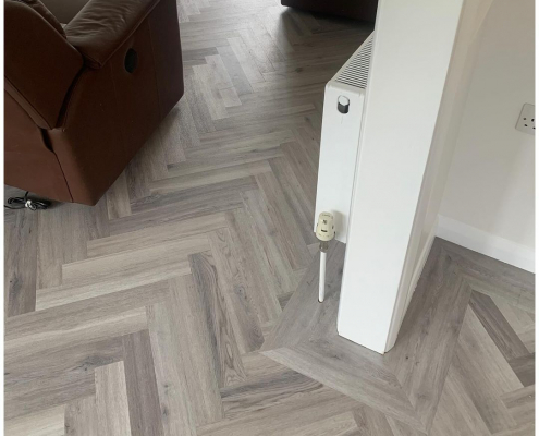 Border detail around doorway opening in light grey herringbone LVT flooring installation Redhill