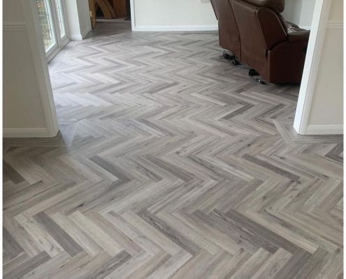 Seamless herringbone LVT flooring flowing through open doorway between rooms in Redhill home