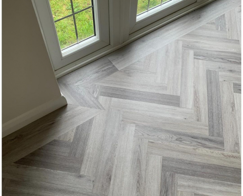 Light grey herringbone LVT flooring with border detail next to leaded French doors in Redhill Surrey home