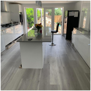 Full view of contemporary white kitchen with grey ash plank LVT flooring and garden through French doors