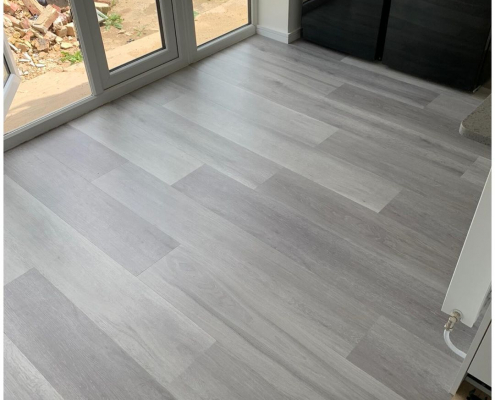 Close-up of grey ash plank LVT flooring near French doors showing light and dark tone variation
