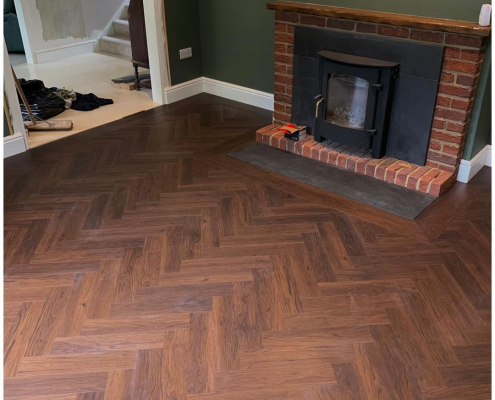 Amtico Spacia Black Walnut herringbone LVT flooring in a cosy Redhill living room with dark green walls and fireplace