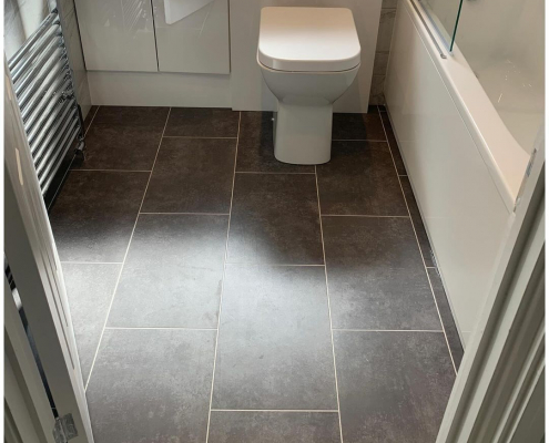 Stone effect graphite LVT flooring in Redhill bathroom with bath, vanity unit and toilet