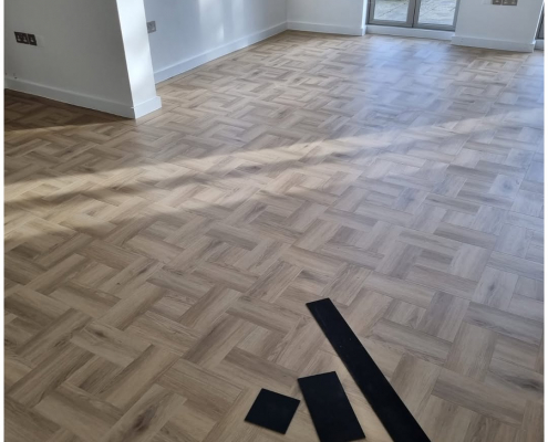Spacious living room with Amtico Signature basket weave LVT flooring and tramline border opening to garden
