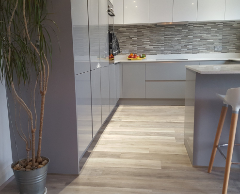 Light oak LVT kitchen flooring installation Light oak plank LVT flooring in Reigate kitchen diner with gloss grey base units and white wall cabinets