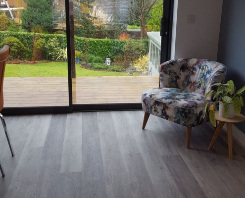 Light oak LVT kitchen diner flooring installation Reigate kitchen diner living area with light oak LVT flooring, floral cocktail chair, and patio doors to garden