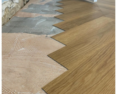 Oak herringbone LVT mid installation Honey oak herringbone LVT being installed showing tiles next to prepared adhesive in Surrey home