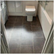 Stone effect graphite LVT flooring in Redhill bathroom with bath, vanity unit and toilet