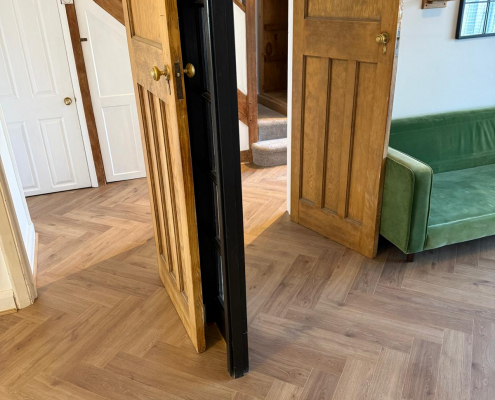 Seamless Herringbone Flooring Throughout Ground Floor Continuous Furlong Manor herringbone laminate flooring flowing between living room, dining area and hallway with seamless transitions throughout the ground floor.