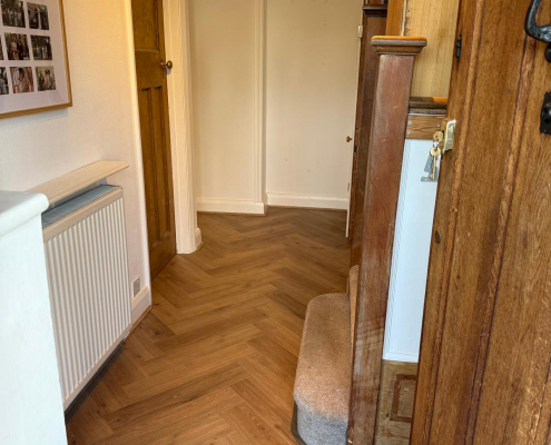 Herringbone Hallway Flooring with Oak Staircase Warm oak effect herringbone laminate flooring installed in hallway with original oak doors, oak staircase and white walls in Surrey home.