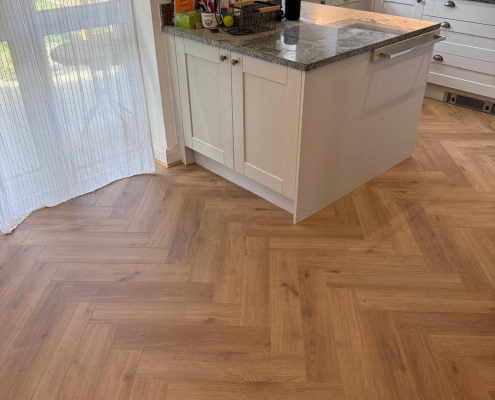 Herringbone Laminate Flooring with Garden French Doors Furlong Manor oak effect herringbone laminate flooring in dining space with grey shaker kitchen and glazed French doors opening to the garden.