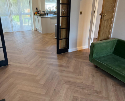 Open Plan Herringbone Flooring Installation in Redhill Surrey Furlong Manor herringbone laminate flooring viewed from living room towards dining area and kitchen with seamless open plan layout.