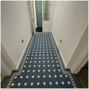 Karndean Heritage LVT flooring installed in a bright Reigate entrance hallway with white walls and white glazed double doors, featuring blue and white diamond tiles with a grey border and inset diamond detailing.