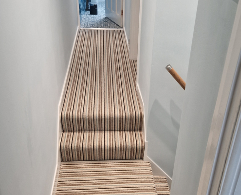 Wool Loop Stair and Landing Carpet Striped wool loop carpet installed on staircase and landing with oak flooring, oak handrail, light blue walls and white woodwork in a bright family home.