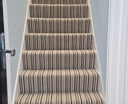 Striped Wool Loop Carpet Installation on Stairs and Landing Striped wool loop carpet installed on staircase and landing with oak flooring, oak handrail and light blue walls in a bright Redhill family home
