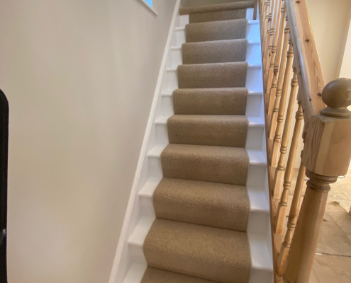 Oak Staircase with Beige Berber Runner View up oak staircase with beige wool loop Berber runner and white painted staircase details