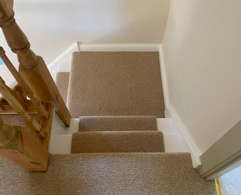Quarter Turn Staircase with Wool Loop Runner Quarter turn staircase with beige wool loop runner leading to fully carpeted landing