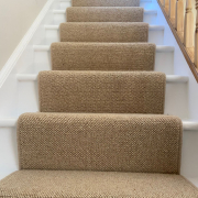 Close up of beige wool loop stair runner fitted to oak stairs with white painted risers and skirting to home in Redhill, Surrey