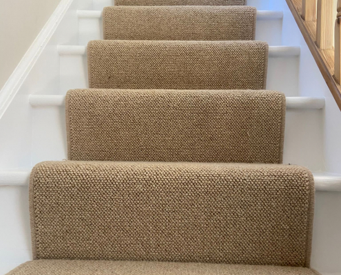 Close Up of Beige Wool Loop Stair Runner Close up of beige wool loop stair runner fitted to oak stairs with white painted risers and skirting to home in Redhill, Surrey