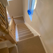 Beige wool loop Berber carpet runner on oak staircase with white painted steps and fully carpeted landing